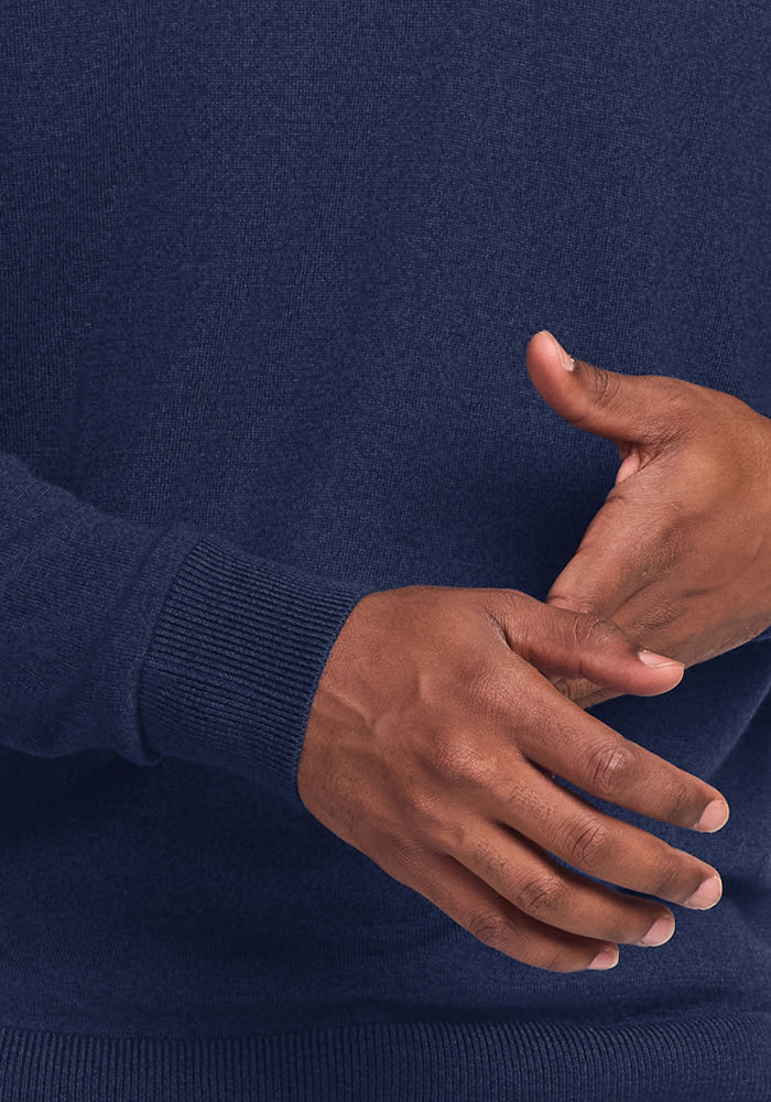 Someone wears the Woolx Enzo Quarter Zip - Ocean Cavern, hands gently clasped in front of their torso.