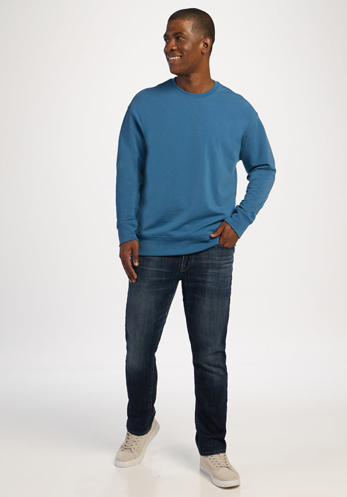 Man wearing a Woolx Miles Crewneck in Blue Ashes, dark blue jeans, and light-colored sneakers.