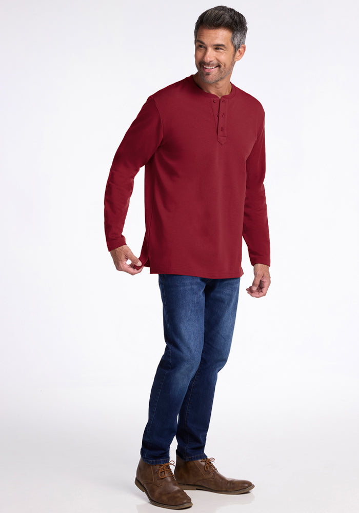 Man in a Woolx Jackson Henley - Pinot Noir, blue jeans, and brown shoes standing and smiling on white background.