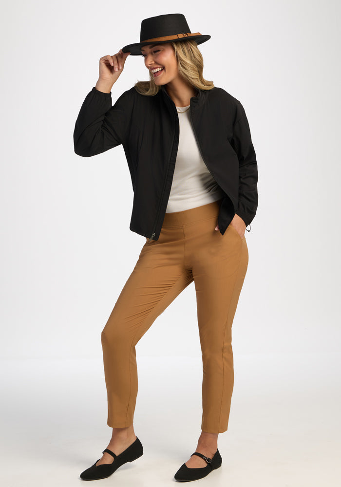Confident model in Woolx Cooper Windbreaker - Black poses against white background, styled with tan pants and a hat.