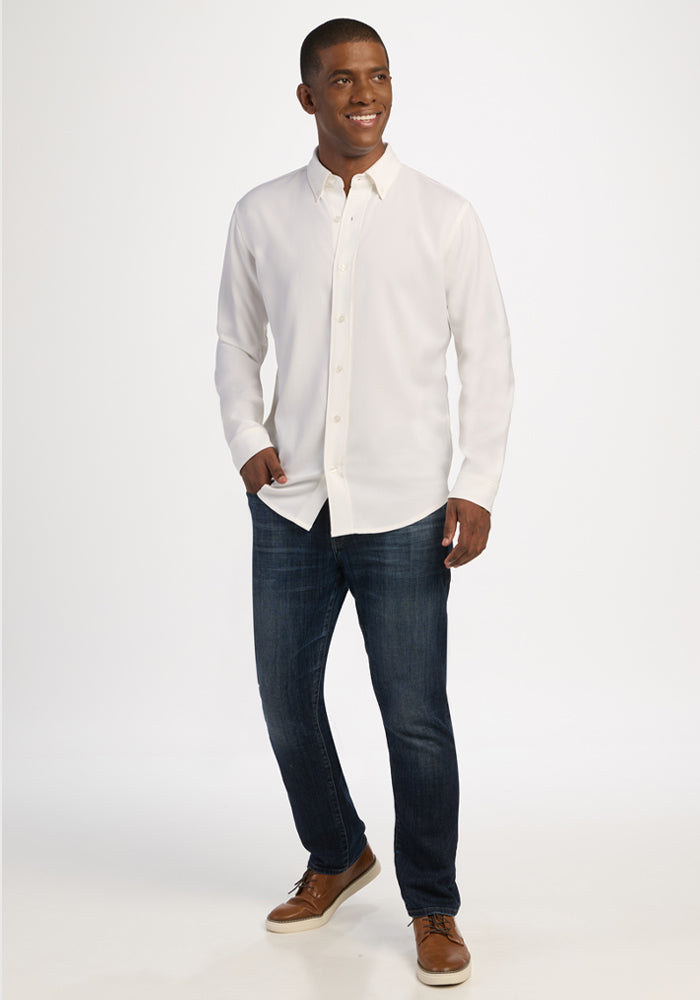 Man in Woolx Nash Button Up - Eggshell, blue jeans, brown shoes, standing and smiling against white background.