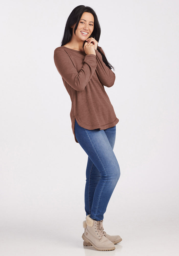 Woman in Woolx Blair Tunic - Sable Heather, blue jeans, and beige boots smiles against a plain white background.