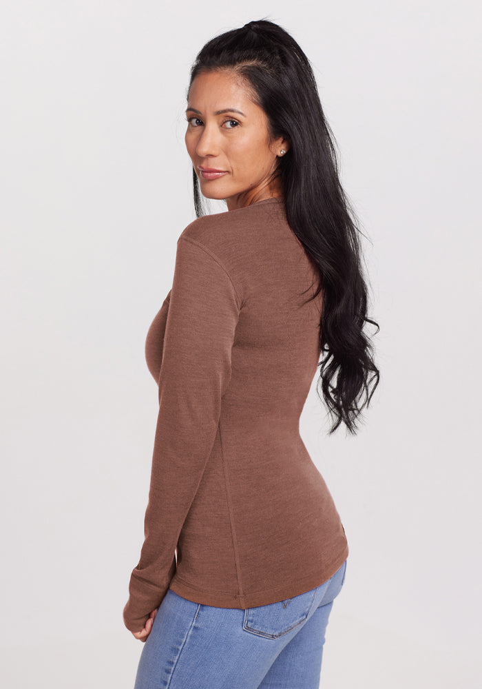 Woman in a Woolx Hannah Long Sleeve Top - Sable Heather and jeans, standing sideways, looking over her shoulder.