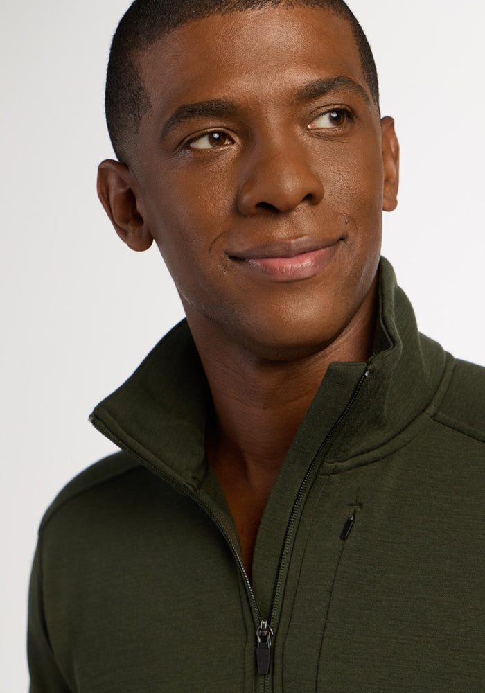 Man in Woolx Mason 1/4 Zip - Duffel Bag, smiling and glancing left against a plain background.