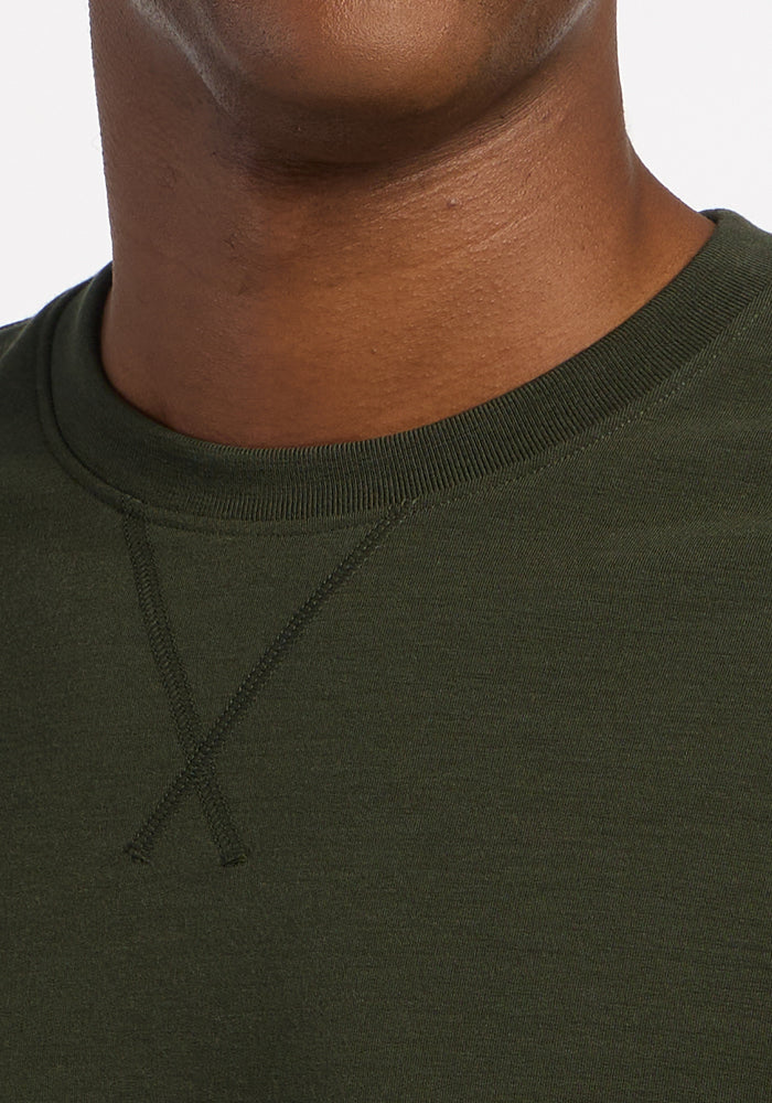 Woolx Miles Crewneck in Duffel Bag olive green merino with moisture-wicking properties and cross-stitch detail.