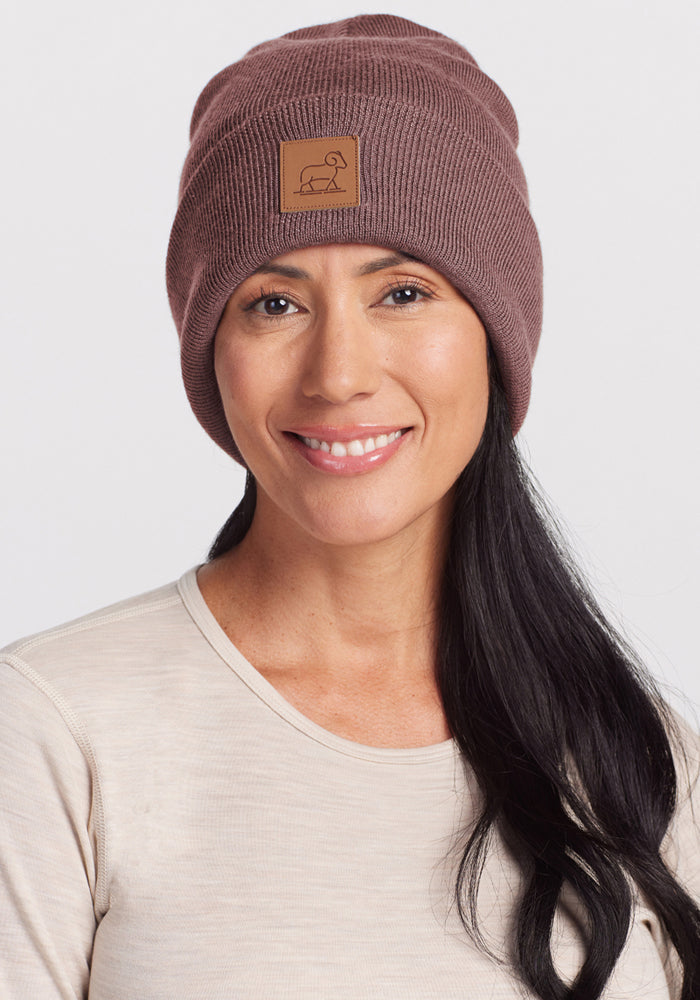 Woman with long black hair in a Woolx Baylor Beanie - Sable Heather and beige shirt, smiling warmly at the camera.