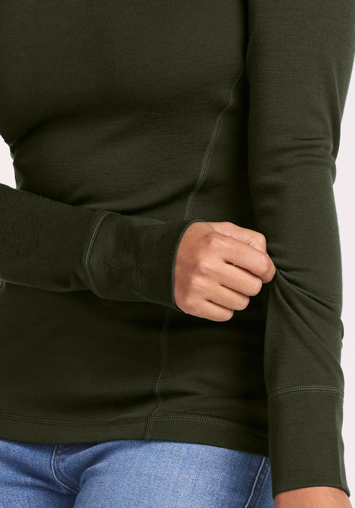 Person in a Woolx Hannah Long Sleeve Top - Duffel Bag, blue jeans, pulling on their right sleeve.