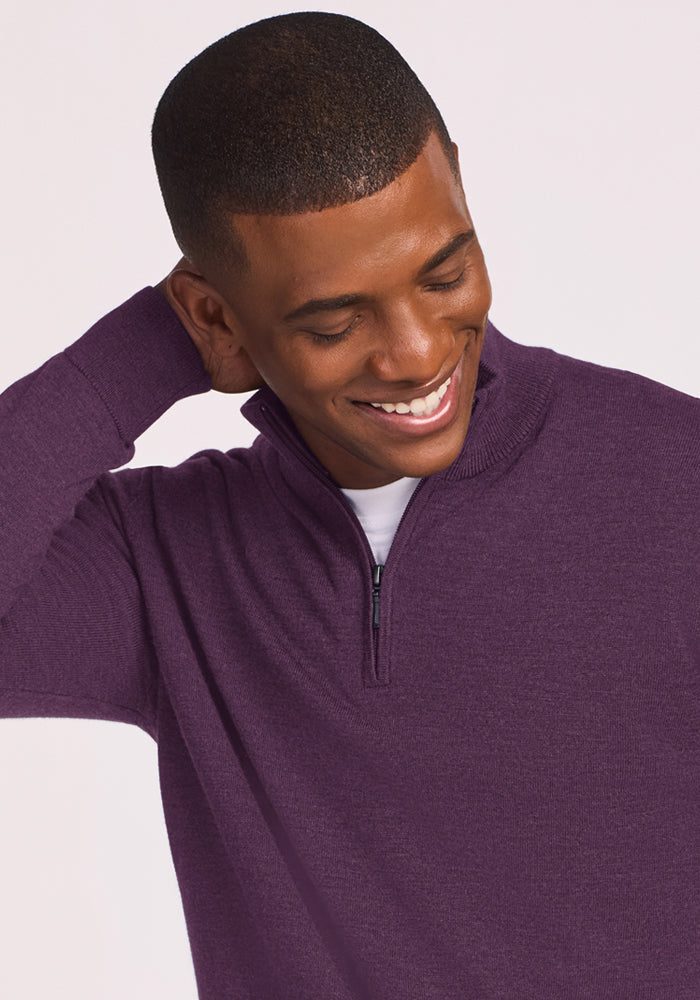 Man in a Woolx Enzo Quarter Zip - Purple Iris smiles, looks down, hand behind neck—ideal for year-round layering.
