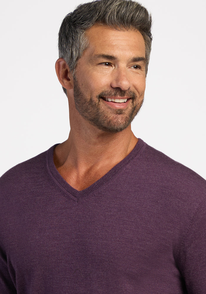 Smiling man with gray hair wears the Woolx Vincenzo Sweater in Purple Iris, a men’s staple, against a white background.