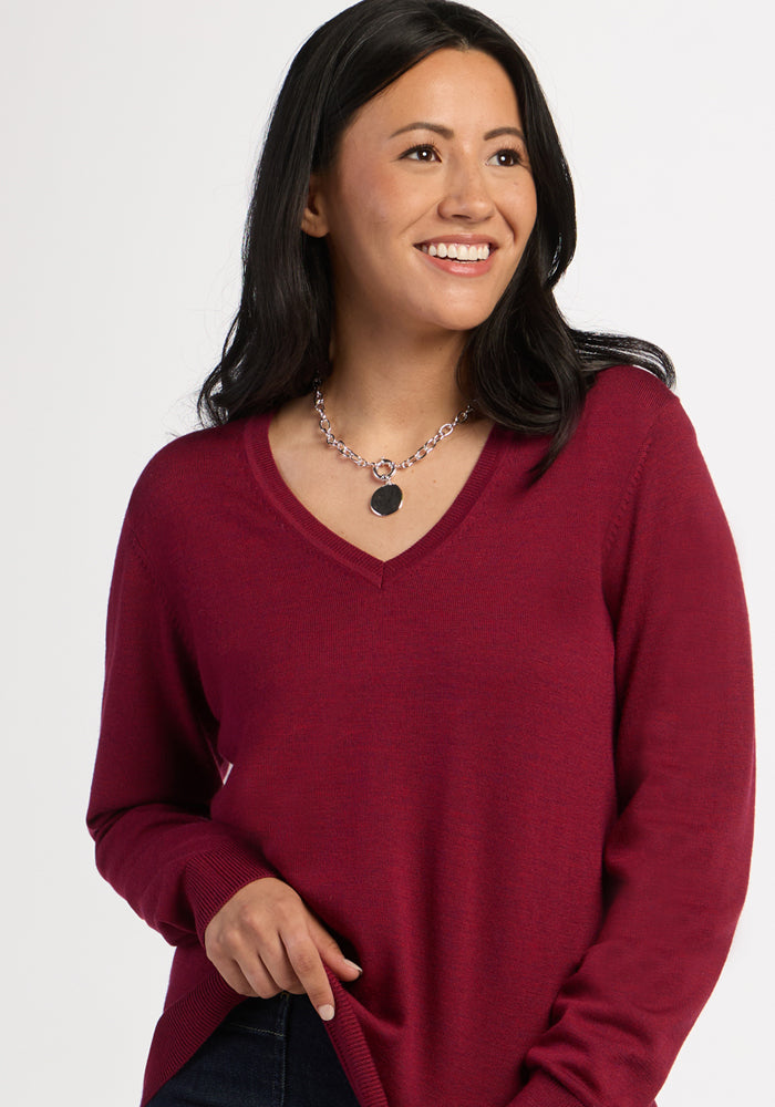 Woman with long dark hair in the Woolx Francesca Sweater in Beet Red, smiling against a plain background.
