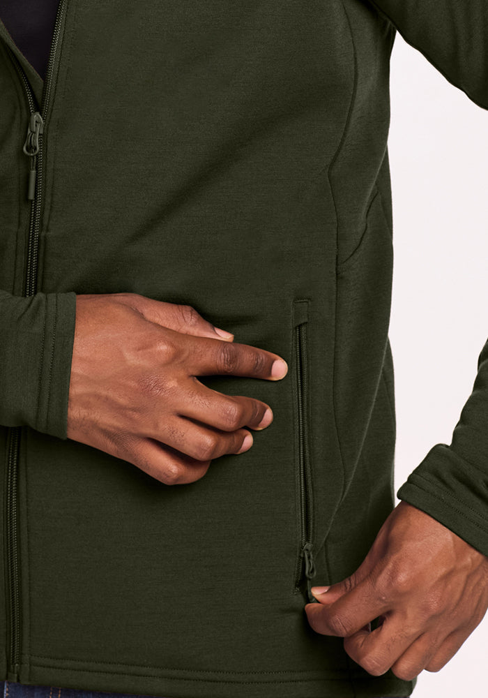 Hands zip the pocket of a Woolx Boulder Hoodie - Duffel Bag, dark green jacket shown.