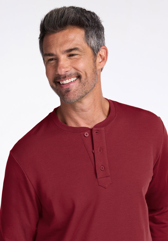 Man with short salt-and-pepper hair in a Woolx Jackson Henley - Pinot Noir, smiling and looking to the side.