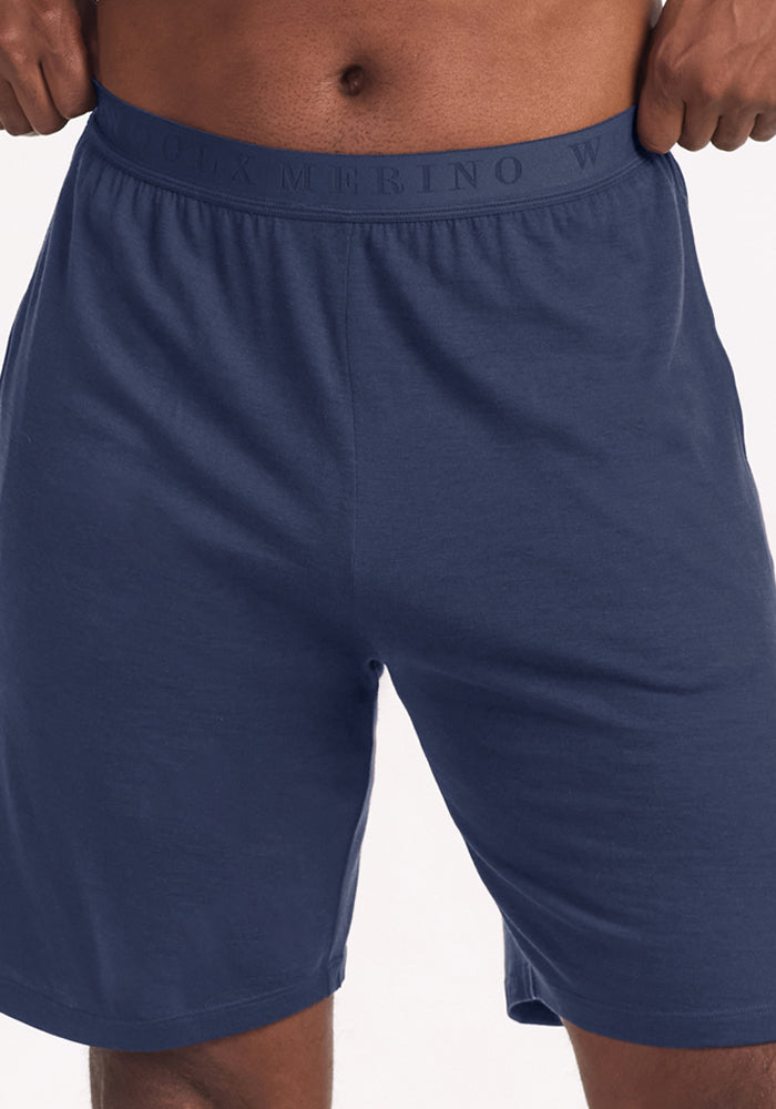 A person wearing dark blue Woolx Archer Lounge Shorts - Deep Dive with an elastic waistband.
