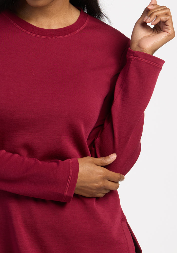 Woman in a Woolx Blair Tunic - Beet Red, one arm crossed, the other hand raised near her shoulder.