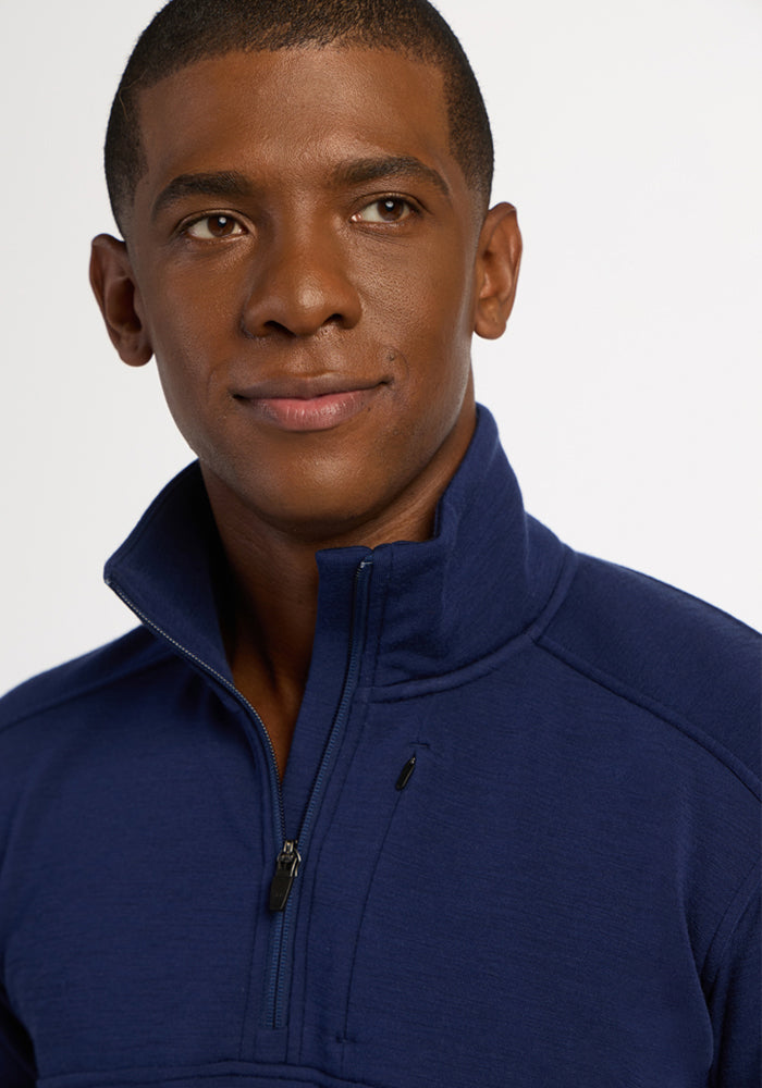Man in a blue Woolx Mason 1/4 Zip - Ocean Cavern smiles slightly to the side, with a neutral background.