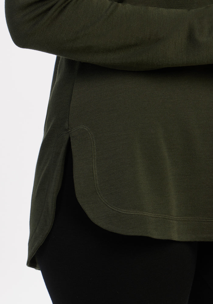 Close-up of a person in the Woolx Blair Tunic - Duffel Bag with a rounded hem, paired with black pants.