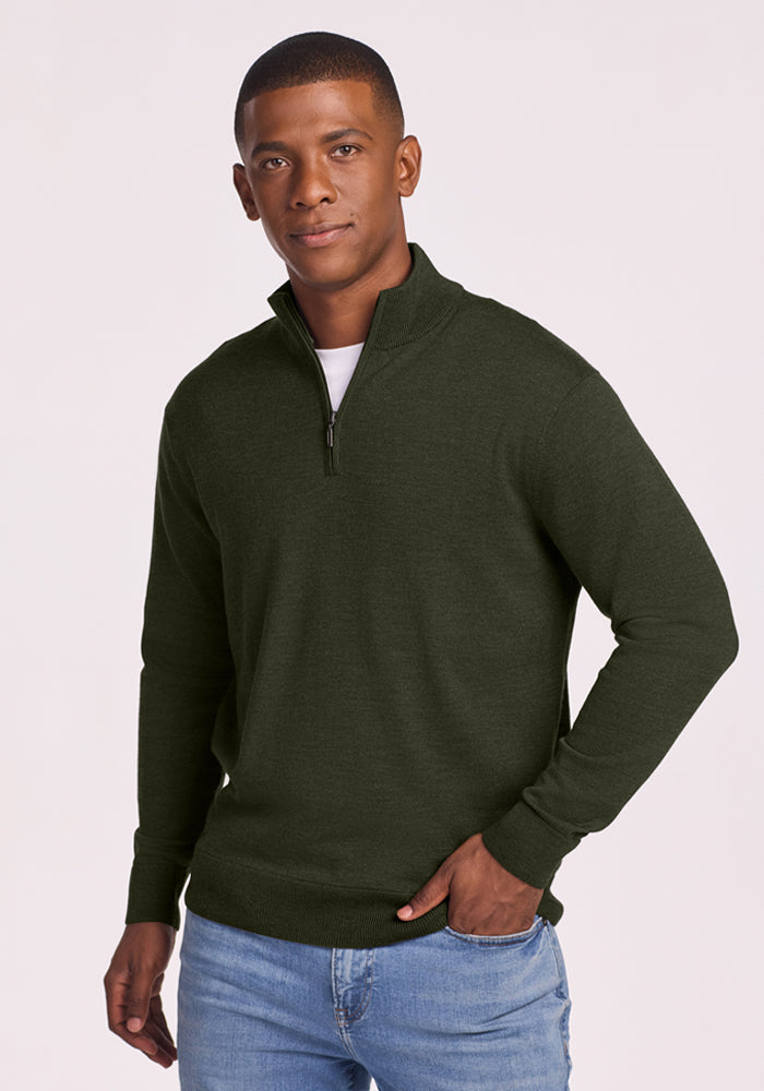 Man in Woolx Enzo Quarter Zip - Duffel Bag and blue jeans stands against a plain background, looking at the camera. 