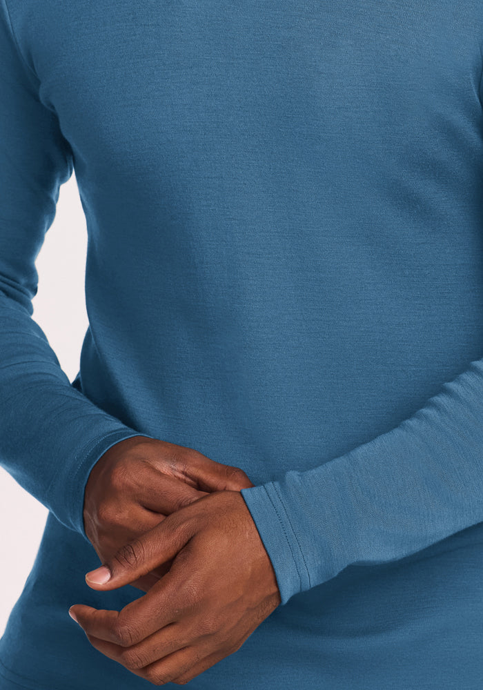 Model wears the Woolx Easton Crew Neck Shirt in Blue Ashes, arms crossed, posed before a plain background.
