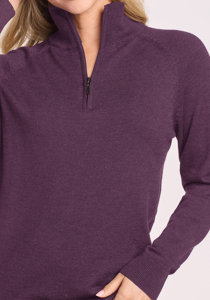 Woman wears Woolx Collins Half Zip Sweater in Purple Iris, hand on hip, against a neutral background.