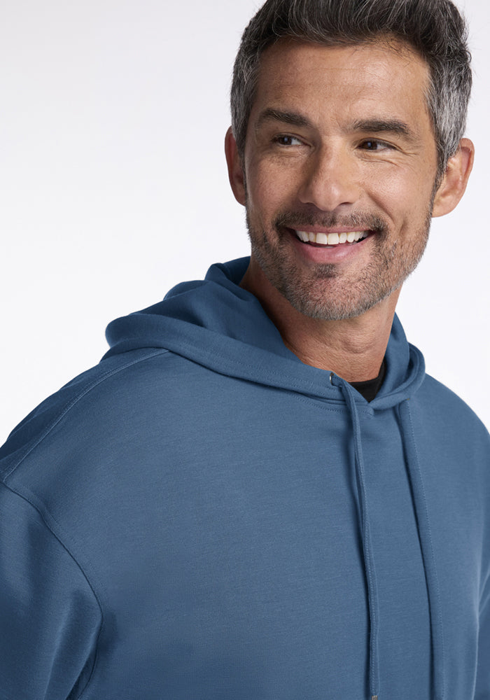 Smiling man in a Woolx Chase Hoodie - Blue Ashes looks to the side against a light background.