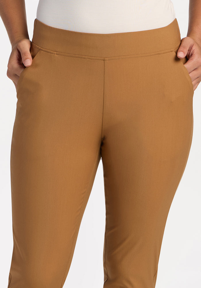 Model wears Woolx Nicole Tall Ankle Pant in Saddleback, hands in pockets, waist to mid-thigh, plain background.
