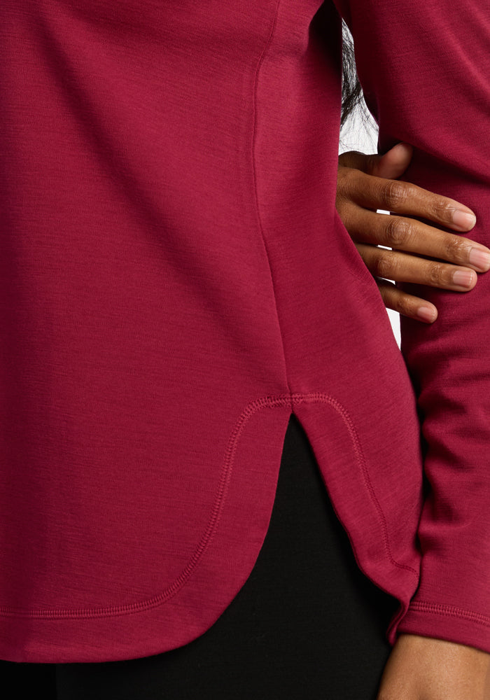A person in a Woolx Blair Tunic - Beet Red, long sleeves, curved hem, hand on hip, against a white background.