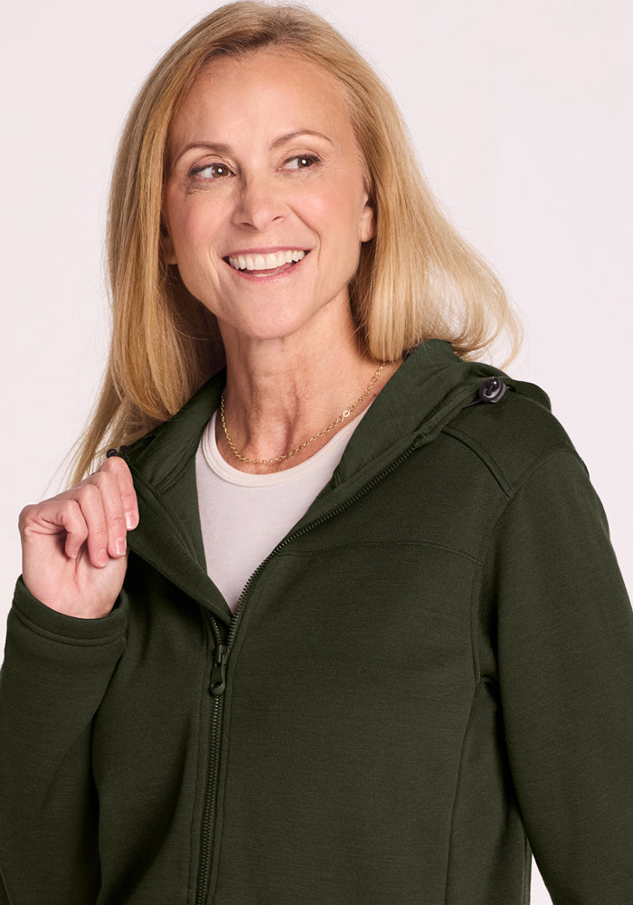 Smiling woman in a Woolx Cubby Hooded Sweatshirt - Duffel Bag, with long blonde hair, looking off to the side.