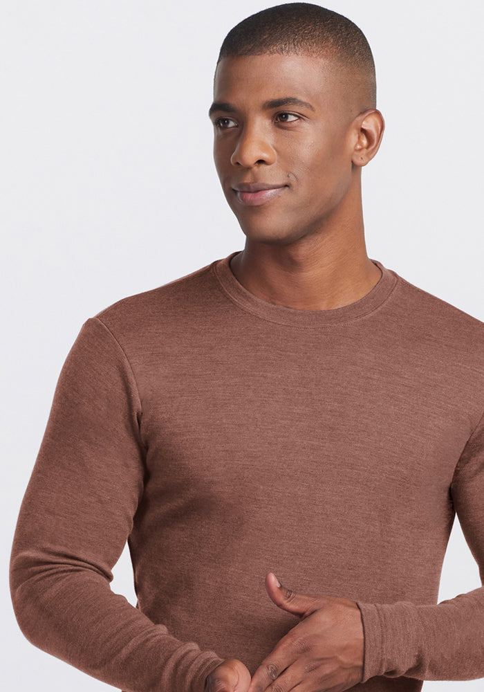Man in Woolx Easton Crew Neck Shirt, Sable Heather, looking aside and smiling with a hand near his waist.