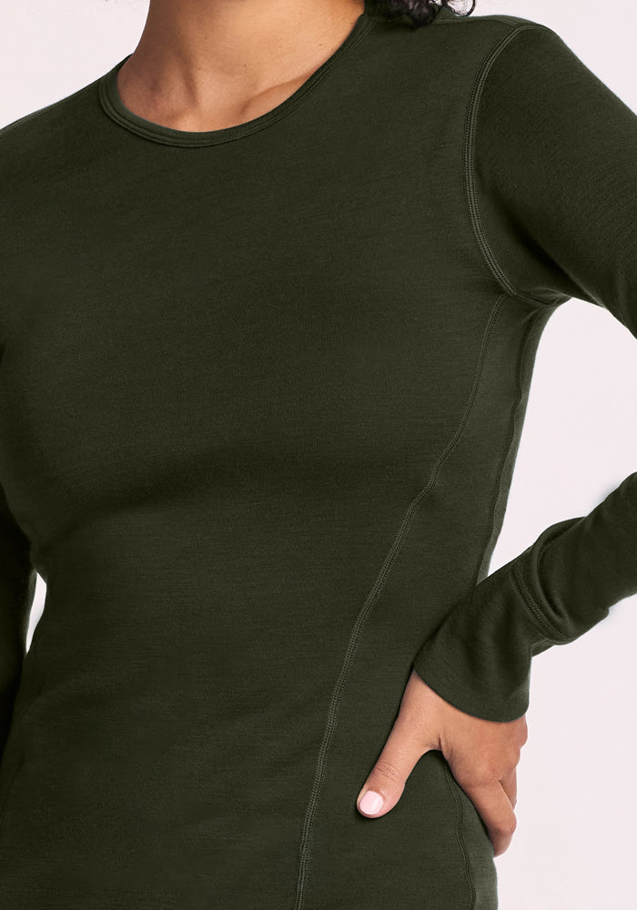 Person wearing a fitted Woolx Hannah Long Sleeve Top in Duffel Bag, with one hand resting on their hip.