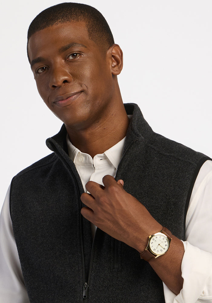 A man wearing a black Everest Vest - Carbon Black moisture-wicking zippered vest over a white button-down shirt.