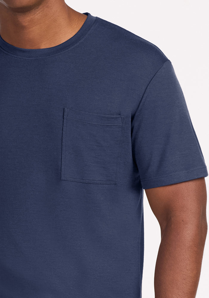 A person wearing a short-sleeved navy blue merino wool Finn Top - Deep Dive sleep tee with a chest pocket.