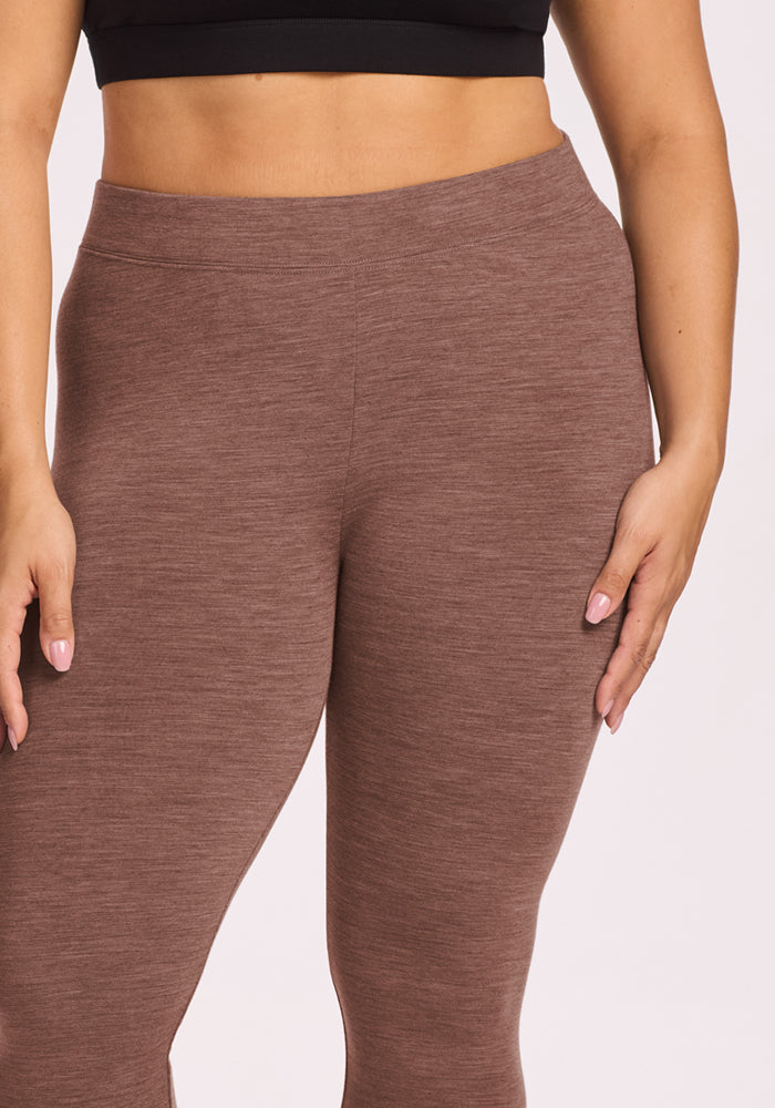 Person in Woolx Stella Leggings - Sable Heather and black crop top, standing with one arm relaxed, one hand on leg.