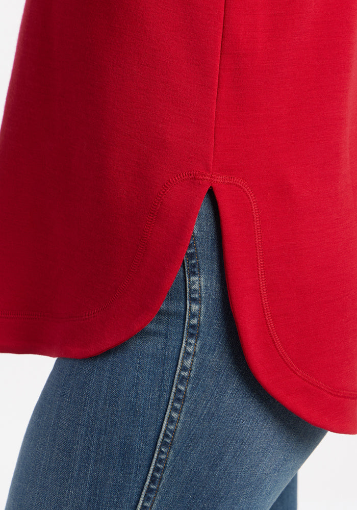 Close-up of the Woolx Blair Tunic in Maraschino Cherry, featuring a scalloped hem over jeans for lightweight warmth.