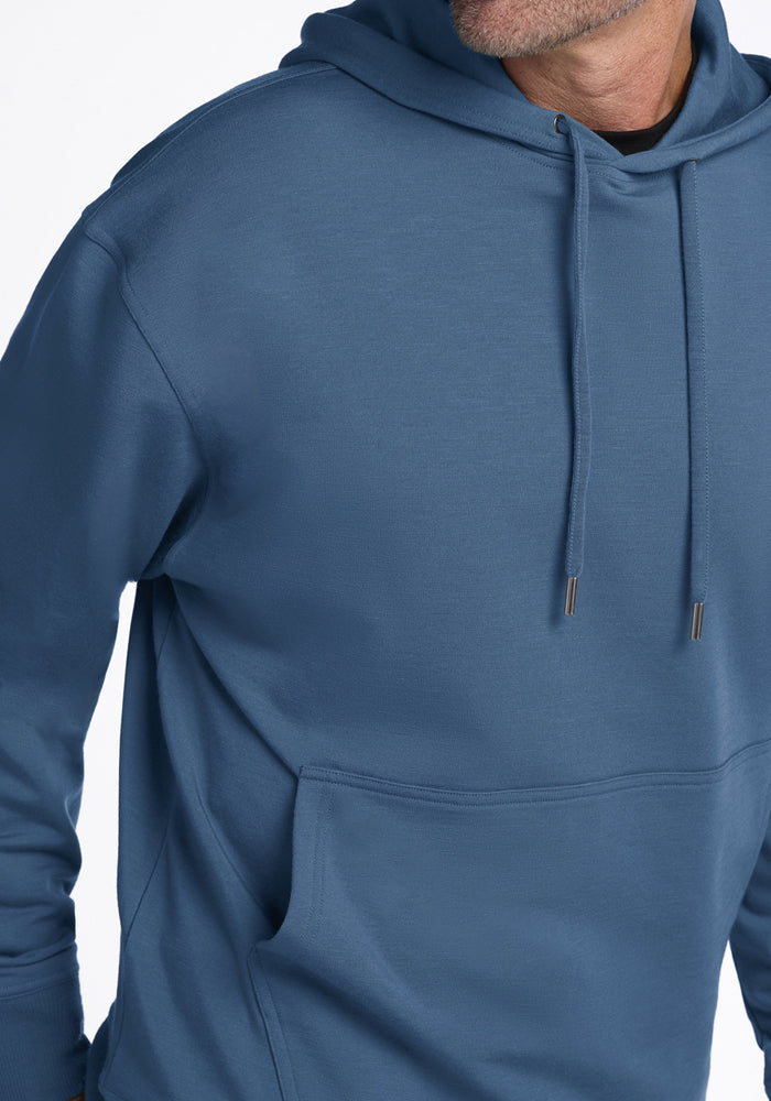 Man in Woolx Chase Hoodie—Blue Ashes; wool, hood, drawstrings, front pocket; shoulder-to-waist view.
