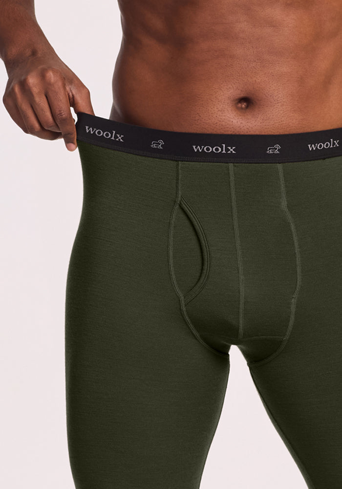 Man showcasing Woolx Backcountry Leggings - Duffel Bag, stretching waistband to display fit, upper body not shown.