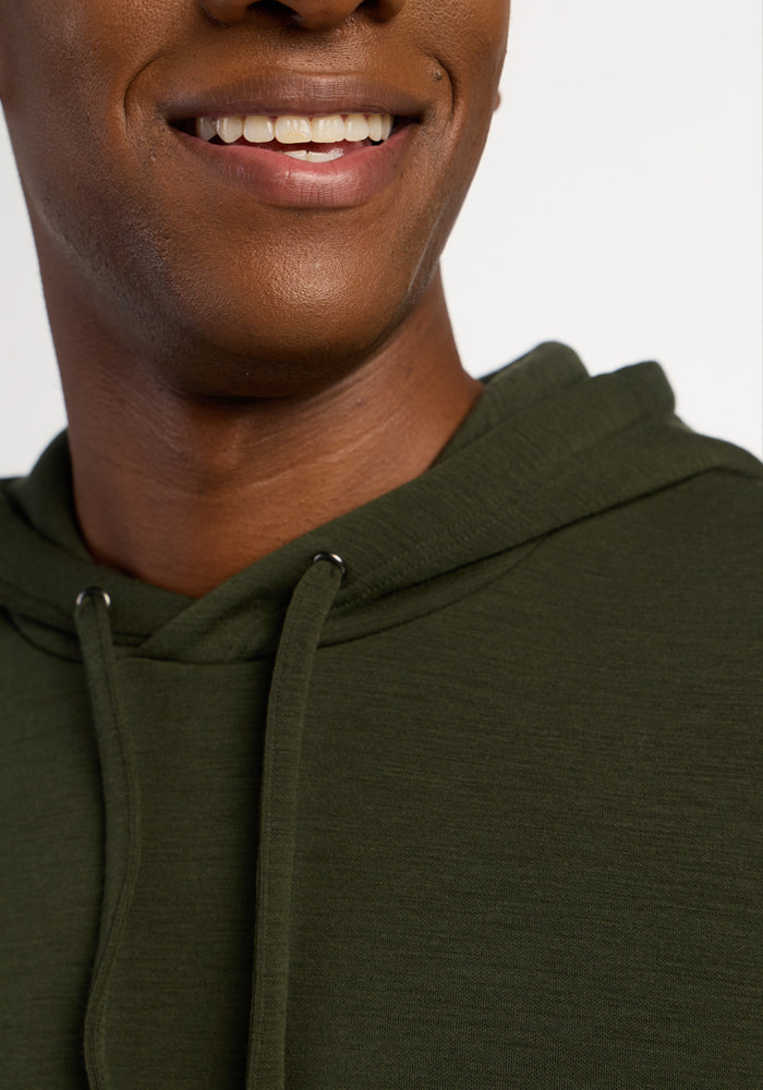 Smiling person in Woolx Watson Pullover - Duffel Bag Merino hoodie, shown shoulders up, on a plain background.