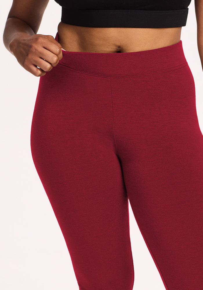 Model in Woolx Stella Leggings - Pinot Noir, holding waistband for a flattering fit.