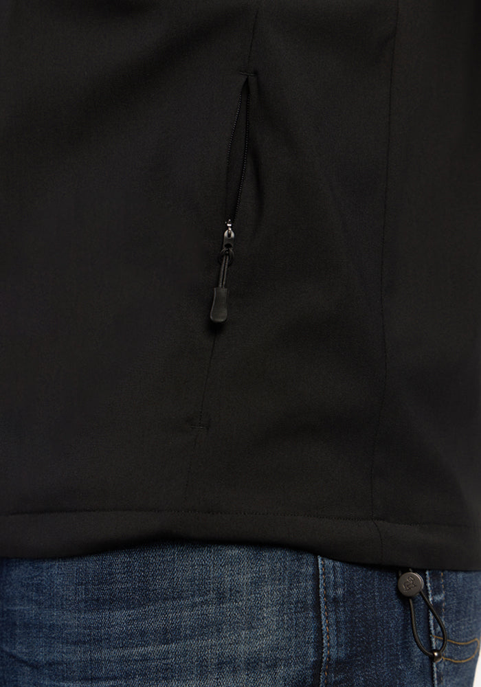 Close-up of the Woolx Dominator Windbreaker in black with zippered pockets, styled over blue jeans.