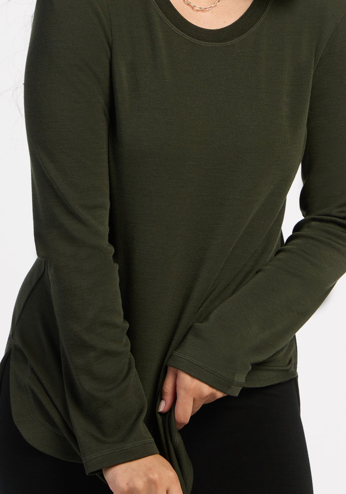 Person in a Woolx Blair Tunic - Duffel Bag and black pants, pulling at the hem; great choice for travel wear.