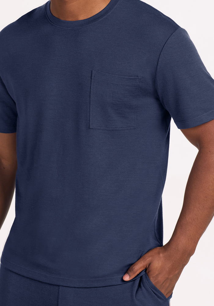 A person wearing a short-sleeved navy blue Woolx Finn Top - Deep Dive lounge shirt with a chest pocket.