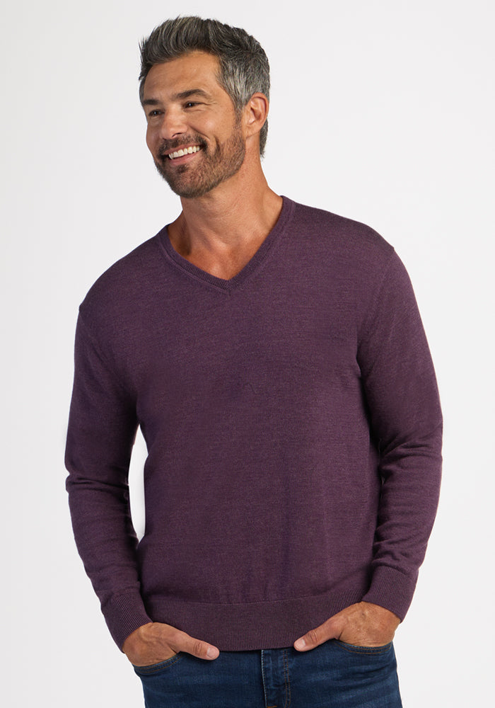 Smiling man wears a Woolx Vincenzo Sweater in Purple Iris, a men’s essential, paired with classic blue jeans.