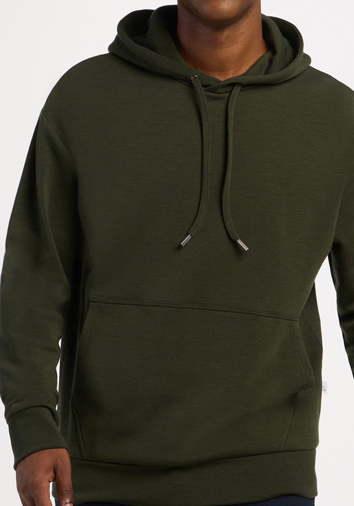 Model wears Woolx Watson Pullover - Duffel Bag, dark green hoodie with drawstrings, shown from shoulders to hips.