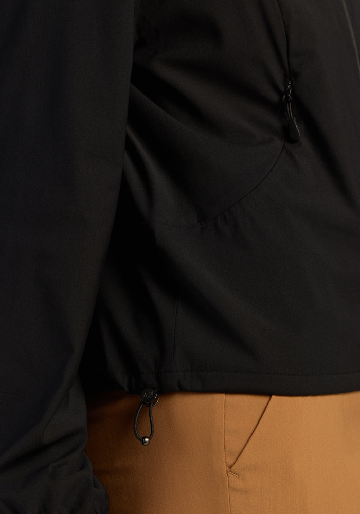 Close-up of a person in the Woolx Cooper Windbreaker - Black, showing drawstring and zippered pocket details.