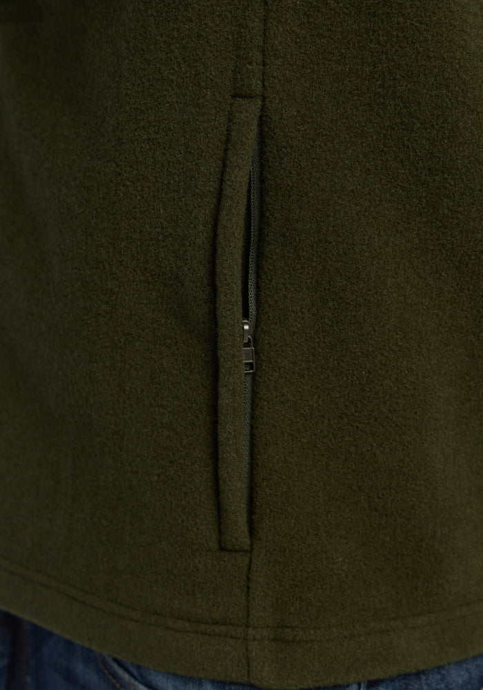 Close-up of a zippered pocket on an olive green heavyweight Merino Woolx Everest Vest - Duffel Bag.