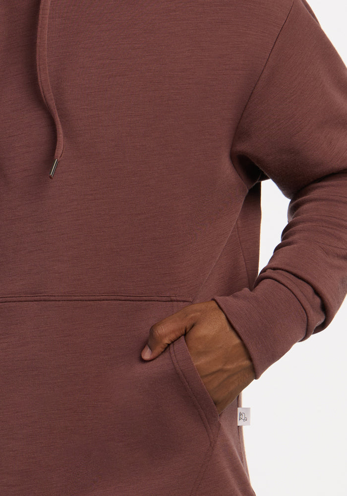 A person wearing the Woolx Watson Pullover in Canyon Clay, one hand in front pocket, shown shoulders to hips.
