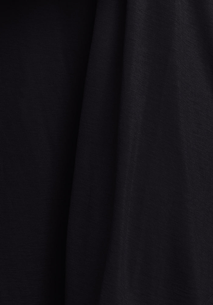 Close-up of the wrinkle-resistant black fabric on the Woolx Ashlie Lounge Top, featuring soft folds and a subtly textured surface that creates gentle shadows and adds depth.