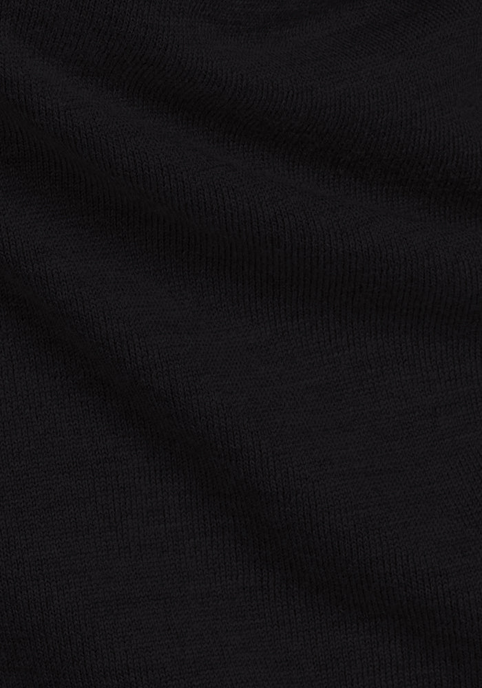 Close-up of Woolx Caitlin Sweater in black, highlighting fine Merino knit texture and diagonal folds.