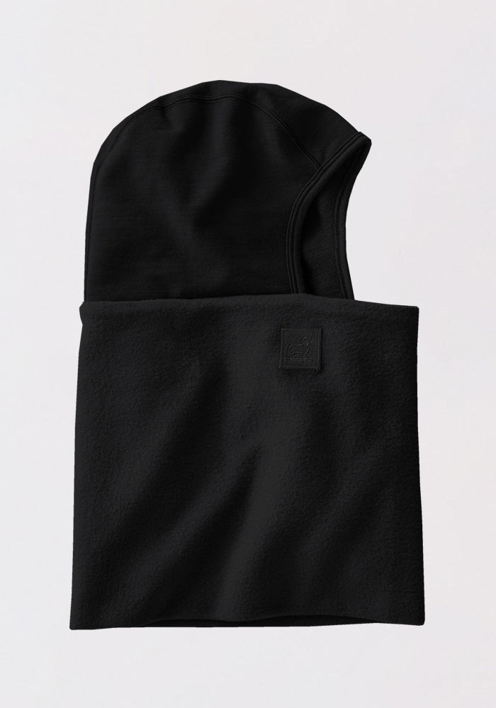 The Woolx Shellaclava - Black is a helmet-compatible merino wool balaclava with a rectangular neck cover, made of smooth fleece for cold weather, shown flat on a light background.