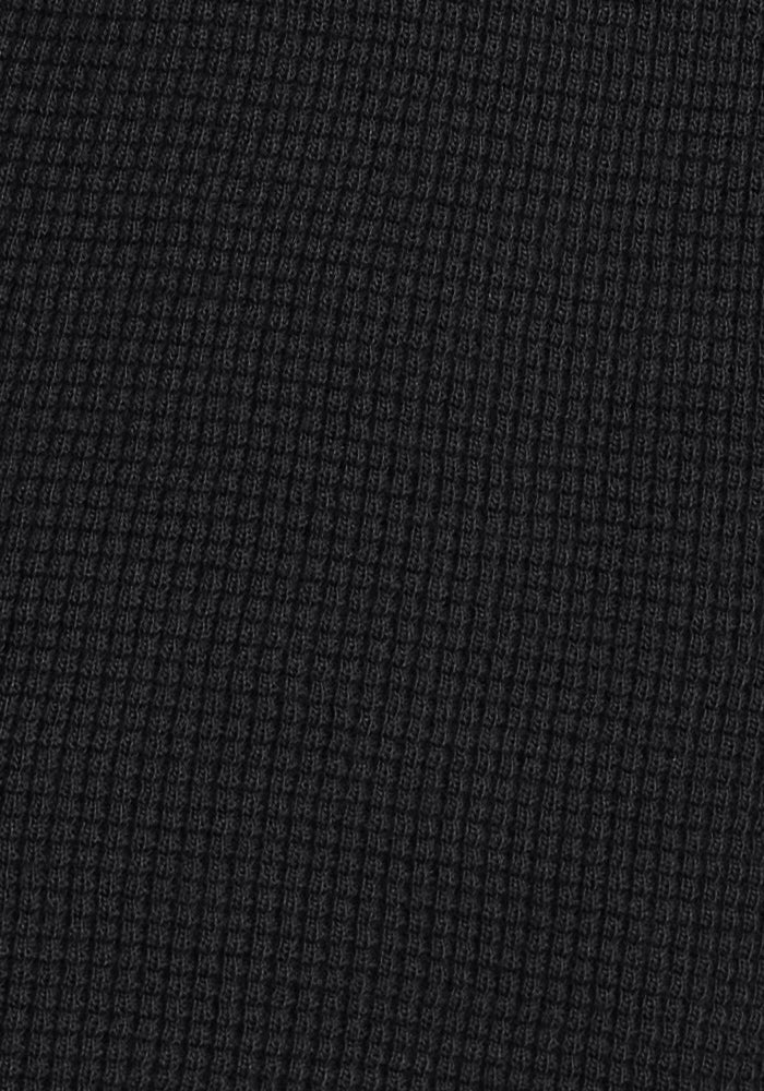 Close-up of the Woolx Oaklynn Waffle Shacket in black, featuring ribbed fabric with a waffle-knit texture and raised square grid—perfect as a warm layering shirt.