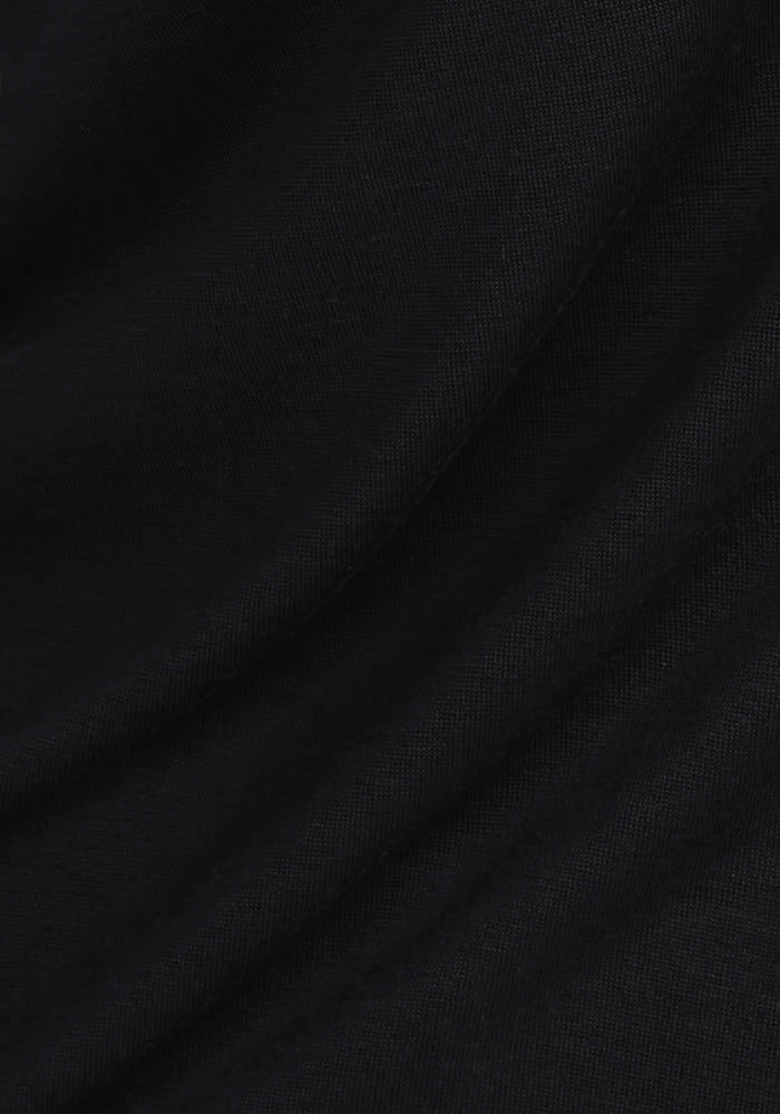 A close-up of smooth, black fabric with soft folds and a gentle texture, reminiscent of the curves and shadows in Woolx Maya Lounge Pants - Black.